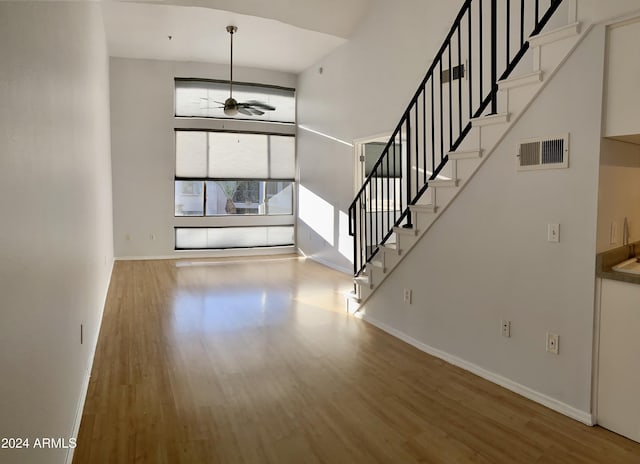 interior space featuring a high ceiling, wood-type flooring, and ceiling fan