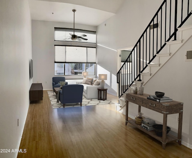 living room featuring hardwood / wood-style flooring, a high ceiling, and ceiling fan