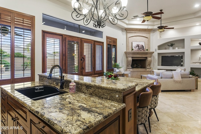 4401 E Taurus Pl, Chandler, AZ 85249 - kitchen featuring a sink, built in shelves, a premium fireplace, a center island with sink, and ceiling fan with notable chandelier
