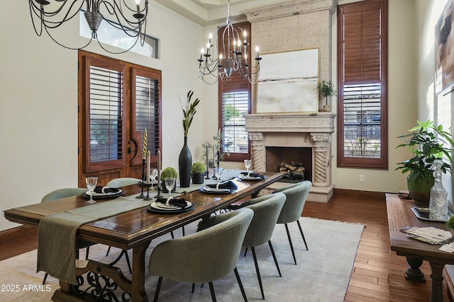 4401 E Taurus Pl, Chandler, AZ 85249 - dining room featuring a premium fireplace, baseboards, a towering ceiling, wood finished floors, and a notable chandelier