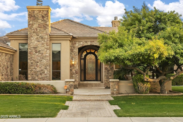 4401 E Taurus Pl, Chandler, AZ 85249 - doorway to property featuring stone siding, a tile roof, a lawn, and a chimney