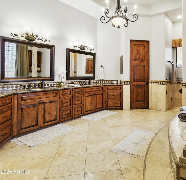 4401 E Taurus Pl, Chandler, AZ 85249 - bathroom featuring tile walls, a chandelier, a towering ceiling, double vanity, and wainscoting