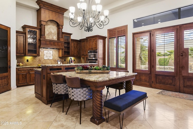 4401 E Taurus Pl, Chandler, AZ 85249 - kitchen with a center island, a chandelier, backsplash, hanging light fixtures, and glass insert cabinets