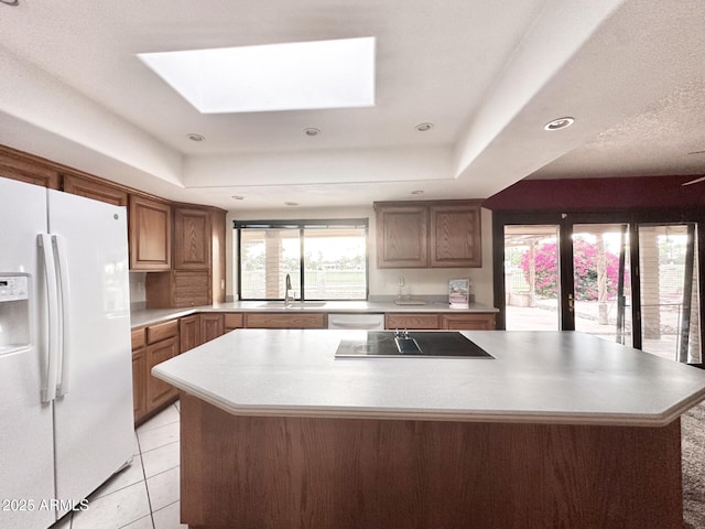 1124 N Villa Nueva Dr, Litchfield Park, AZ 85340 - kitchen featuring white appliances, a skylight, a center island, a sink, and light countertops