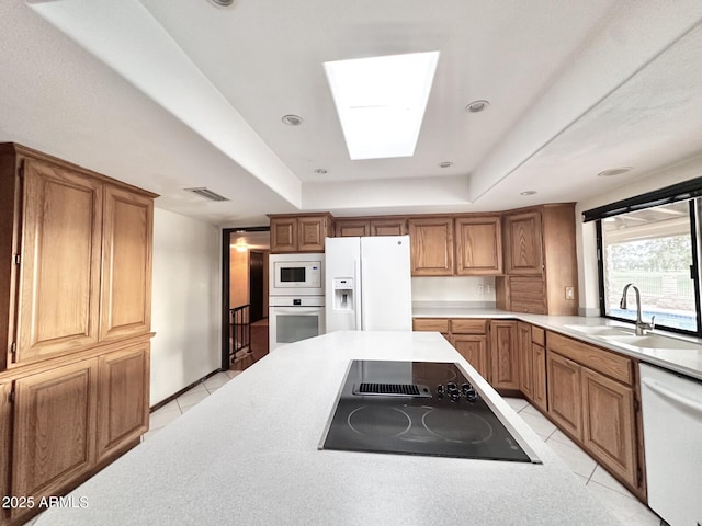 1124 N Villa Nueva Dr, Litchfield Park, AZ 85340 - kitchen featuring white appliances, a sink, light tile patterned floors, a skylight, and brown cabinets