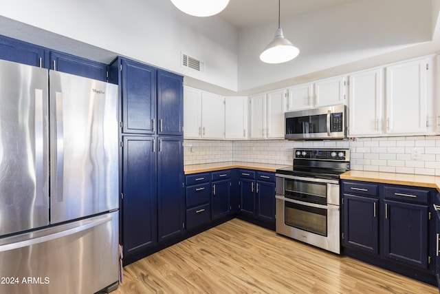 kitchen featuring white cabinets, decorative light fixtures, appliances with stainless steel finishes, and tasteful backsplash