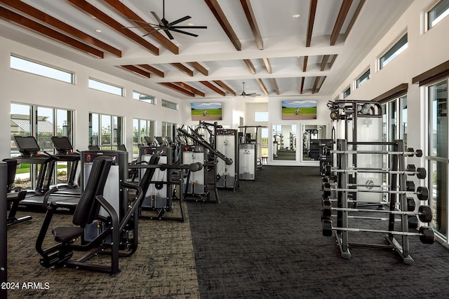 gym with a high ceiling, dark carpet, and ceiling fan