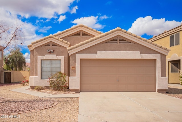 view of front facade featuring stucco siding, a garage, driveway, and fence