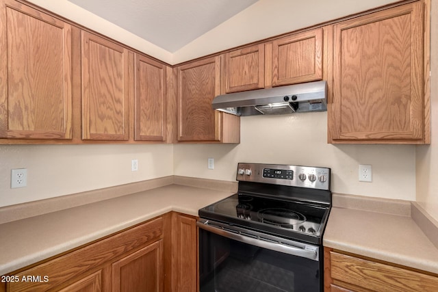 kitchen featuring electric stove, under cabinet range hood, brown cabinetry, light countertops, and lofted ceiling