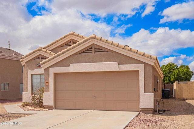 view of front of property featuring stucco siding, concrete driveway, an attached garage, and fence