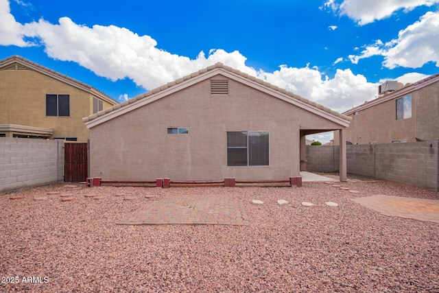 rear view of house featuring a fenced backyard, stucco siding, and a patio