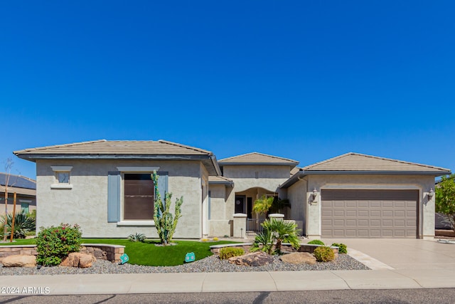 view of front facade with stucco siding, an attached garage, driveway, and a tiled roof