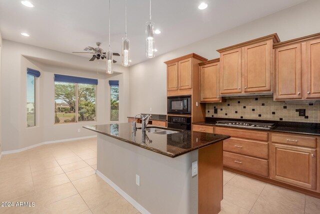 kitchen with black appliances, a sink, backsplash, dark stone counters, and light tile patterned flooring