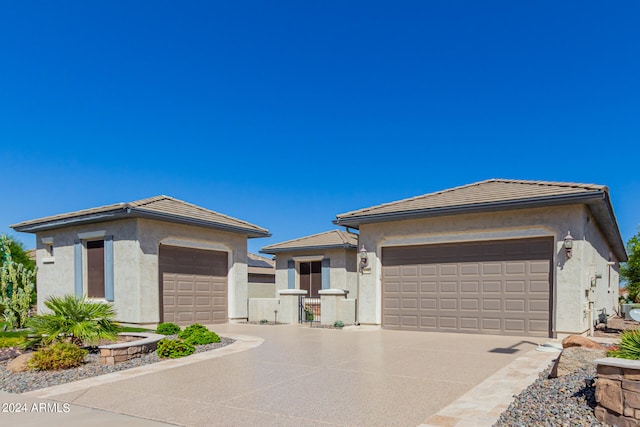 prairie-style home featuring a tile roof, an attached garage, and stucco siding