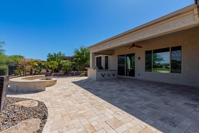 view of patio with an outdoor kitchen, ceiling fan, and an outdoor fire pit