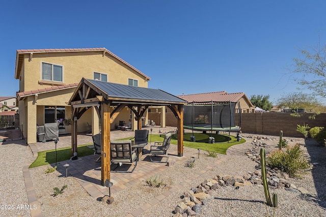 26842 N 176th Ln, Surprise, AZ 85387 - rear view of house with a trampoline, stucco siding, a patio area, a fenced backyard, and a gazebo