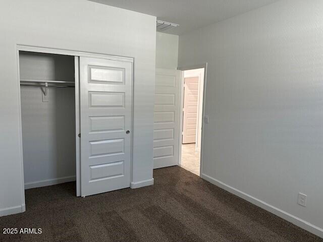 38055 W Excussare Way, Maricopa, AZ 85138 - unfurnished bedroom featuring dark colored carpet, a closet, and baseboards
