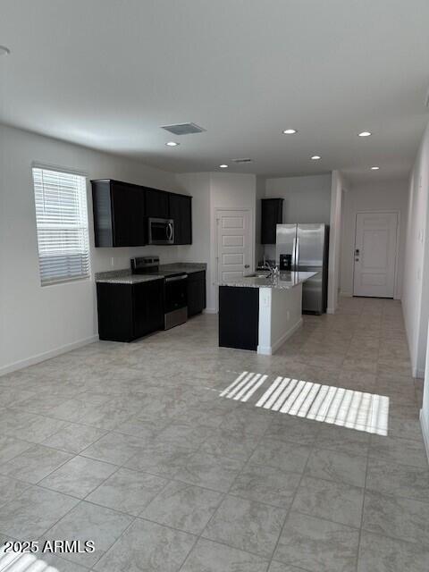 38055 W Excussare Way, Maricopa, AZ 85138 - kitchen with appliances with stainless steel finishes, dark cabinetry, recessed lighting, an island with sink, and open floor plan