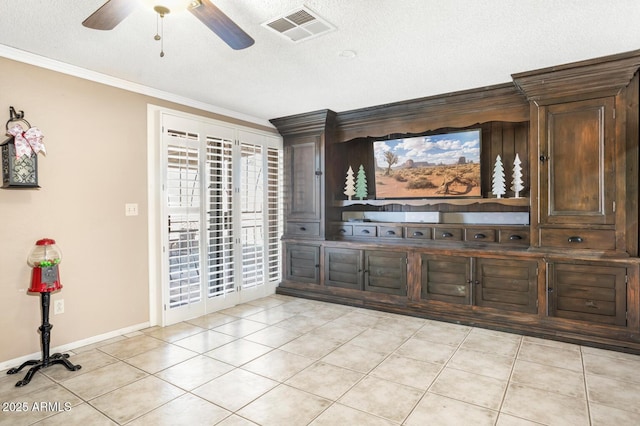 bar featuring ceiling fan, light tile patterned flooring, ornamental molding, a textured ceiling, and dark brown cabinets