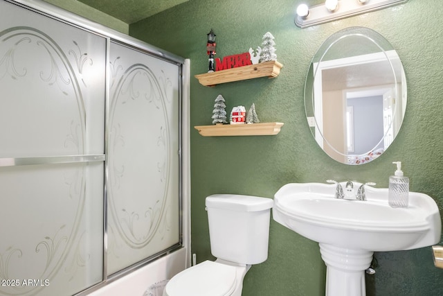 bathroom featuring combined bath / shower with glass door and toilet