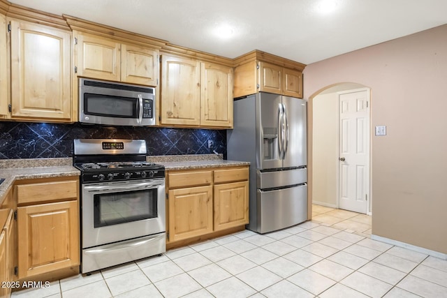 kitchen featuring light tile patterned flooring, light brown cabinetry, stainless steel appliances, and decorative backsplash