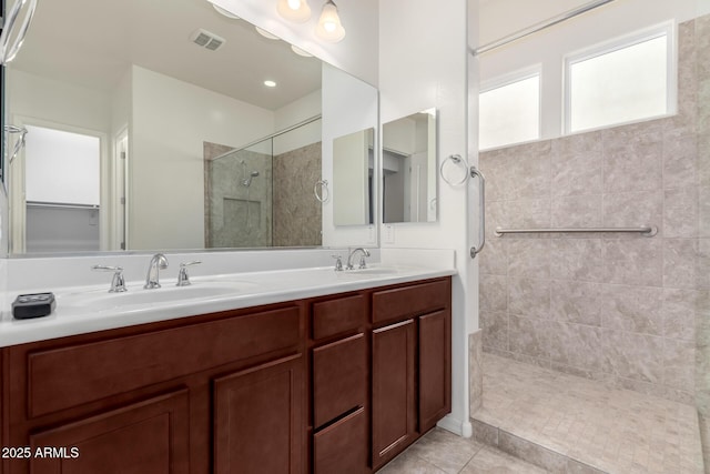 bathroom with a tile shower, tile patterned flooring, and vanity