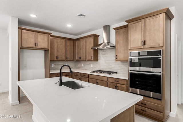 kitchen with wall chimney exhaust hood, stainless steel appliances, a sink, backsplash, and light countertops