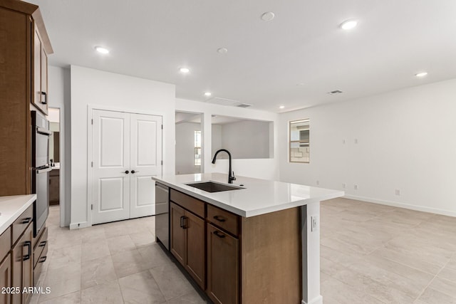 kitchen featuring a sink, stainless steel appliances, light countertops, a center island with sink, and recessed lighting
