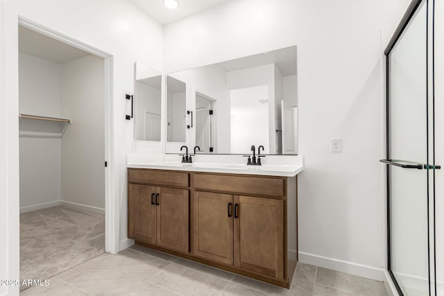 full bath with baseboards, double vanity, a spacious closet, and tile patterned floors