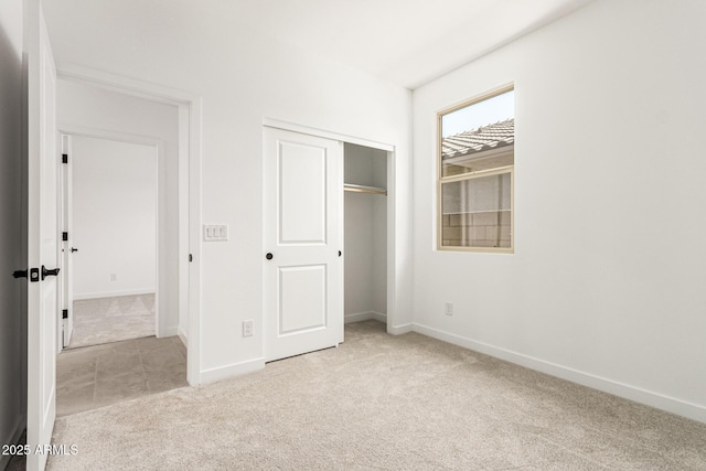 unfurnished bedroom with light carpet, a closet, and baseboards