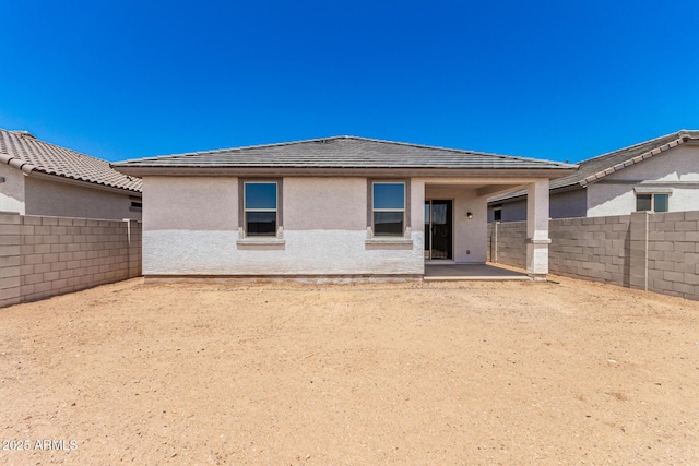 rear view of house featuring a fenced backyard, stucco siding, and a patio