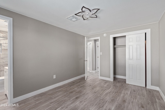 unfurnished bedroom with ensuite bath, light hardwood / wood-style floors, and a closet