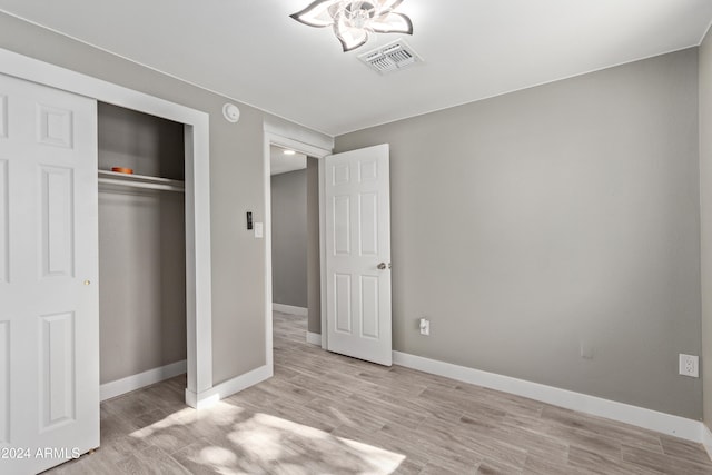 unfurnished bedroom with a closet and light hardwood / wood-style floors