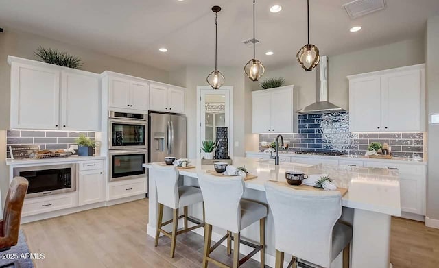16342 W Jackson St, Goodyear, AZ 85338 - kitchen with stainless steel appliances, wall chimney range hood, tasteful backsplash, a breakfast bar, and light countertops