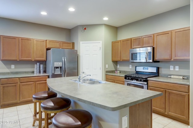 kitchen with appliances with stainless steel finishes, sink, a center island with sink, and light tile patterned floors