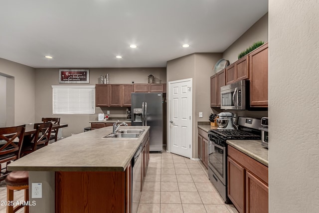 kitchen with sink, a breakfast bar, a kitchen island with sink, stainless steel appliances, and light tile patterned flooring