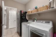 clothes washing area with light tile patterned floors and washing machine and dryer