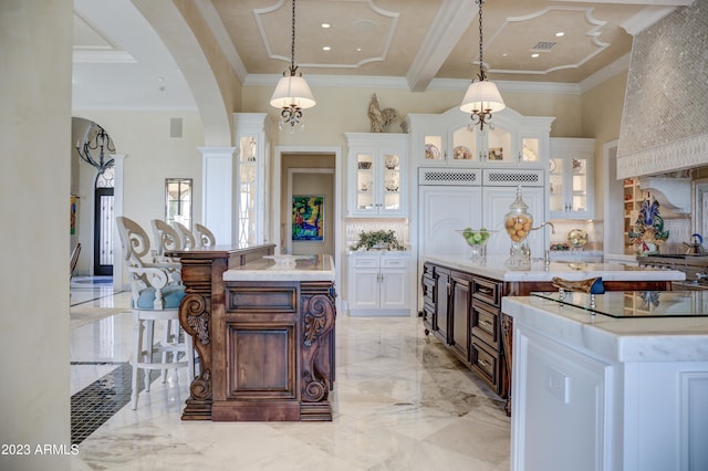 kitchen featuring dark brown cabinets, white cabinetry, pendant lighting, and a kitchen island with sink