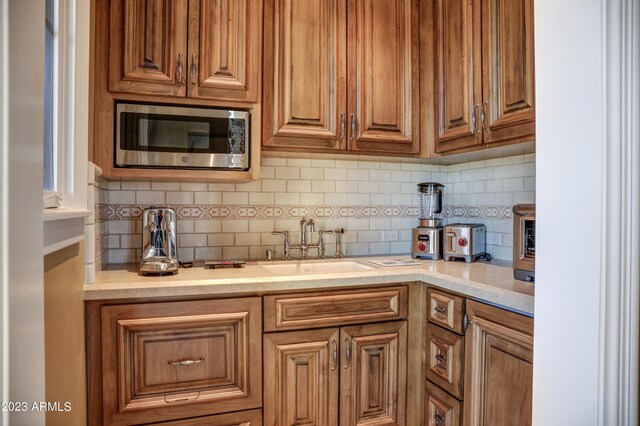 kitchen with decorative backsplash, stainless steel microwave, and sink