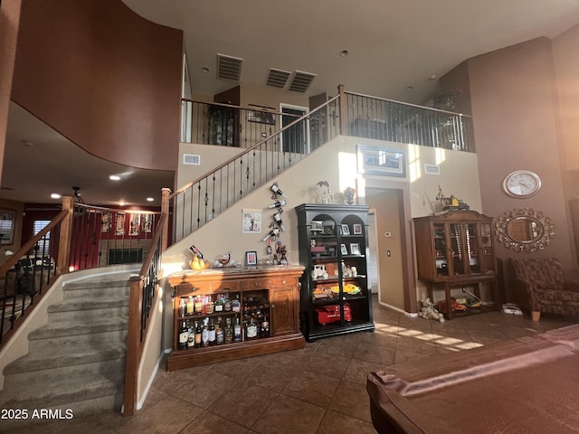 staircase with tile patterned floors and a high ceiling