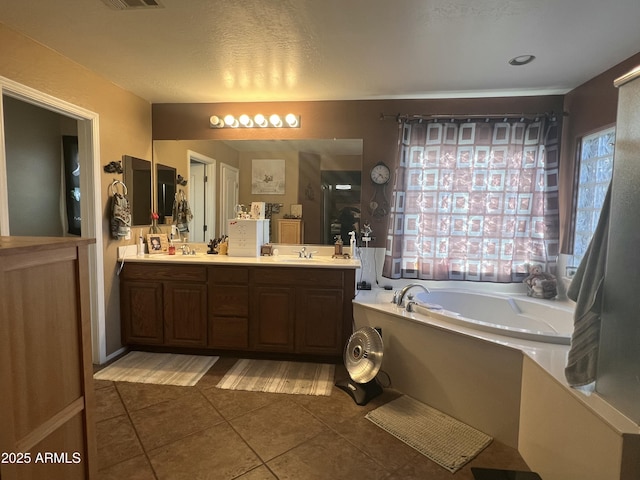 bathroom featuring a healthy amount of sunlight, vanity, tile patterned flooring, and a tub