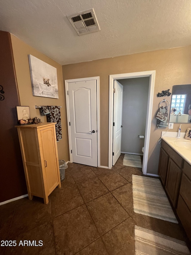 bathroom featuring tile patterned floors, vanity, toilet, and a textured ceiling