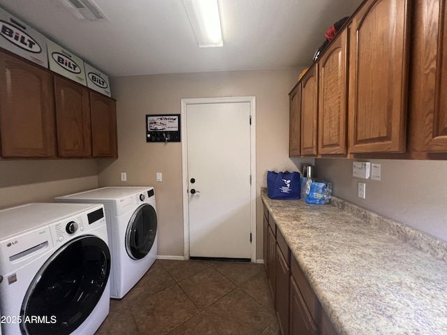 laundry room featuring washer and dryer, dark tile patterned flooring, and cabinets