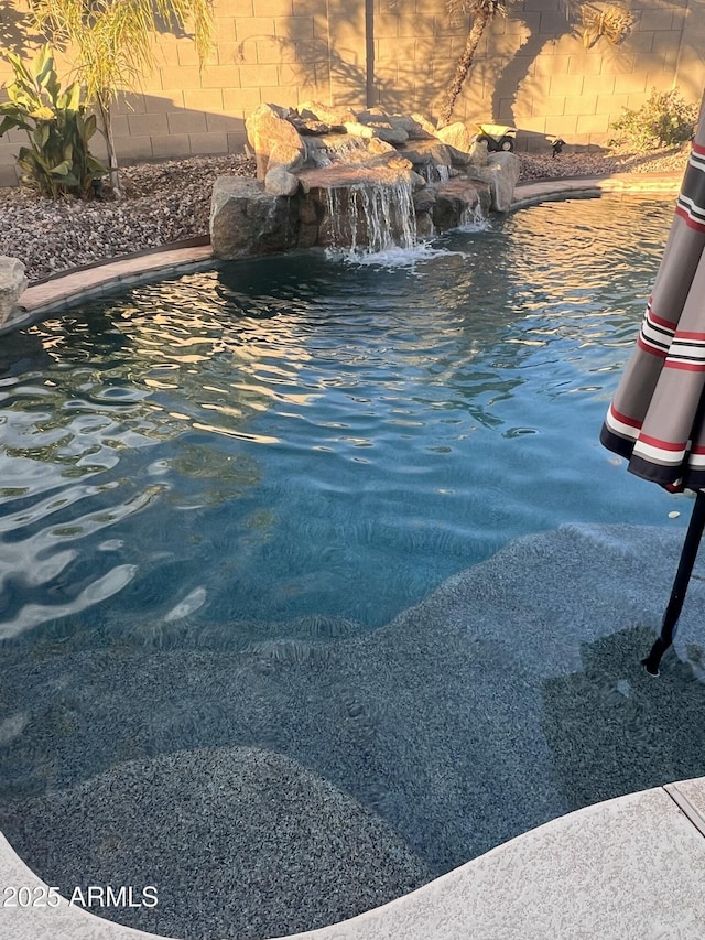 view of swimming pool with pool water feature