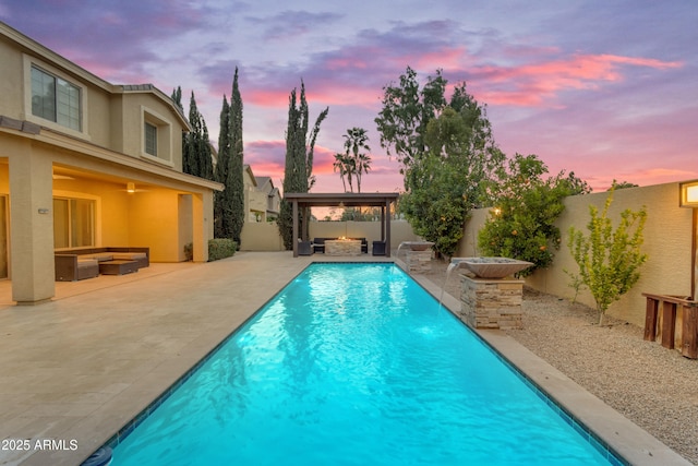 pool at dusk featuring a fenced backyard, a patio area, and an outdoor hangout area