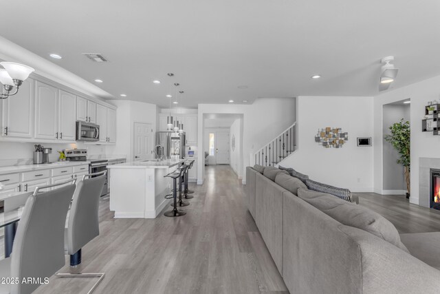 living area featuring light wood-style floors, stairs, visible vents, and recessed lighting