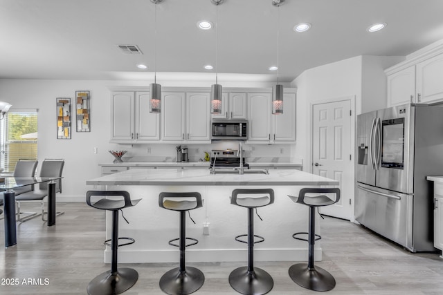 kitchen with visible vents, baseboards, a sink, light wood-type flooring, and appliances with stainless steel finishes