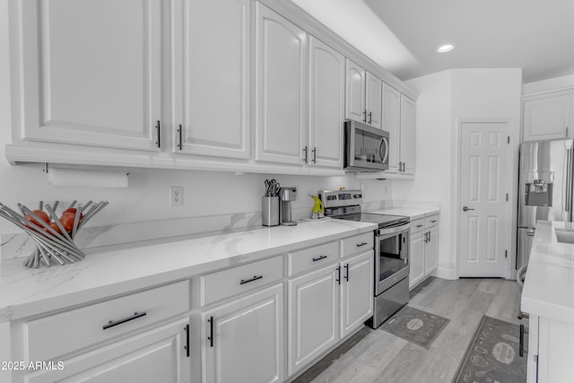 kitchen featuring light stone countertops, light wood-type flooring, white cabinetry, recessed lighting, and appliances with stainless steel finishes