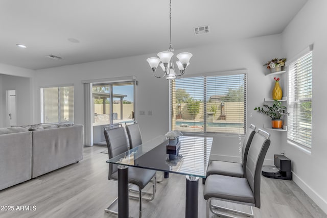 dining area featuring a notable chandelier, visible vents, light wood-type flooring, and baseboards