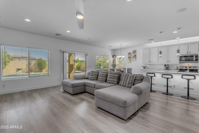 living room featuring light wood-style flooring, baseboards, visible vents, and recessed lighting